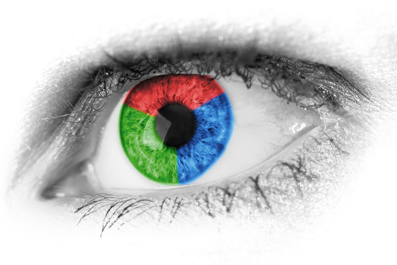 Close up of eye with iris split into red, blue, and green. 